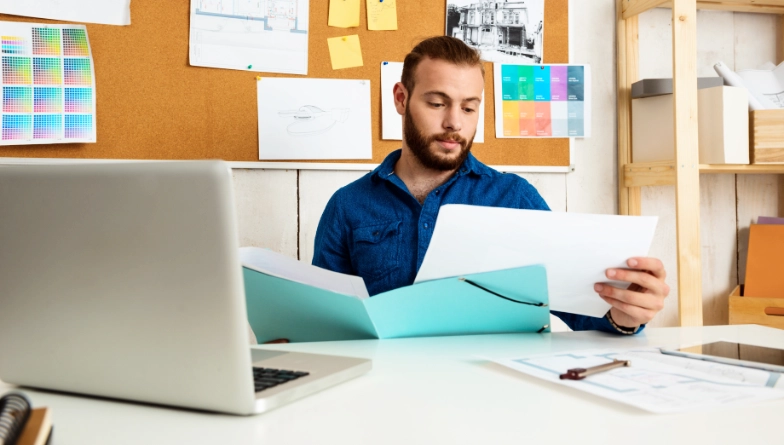 Man looking at print documents at desk
